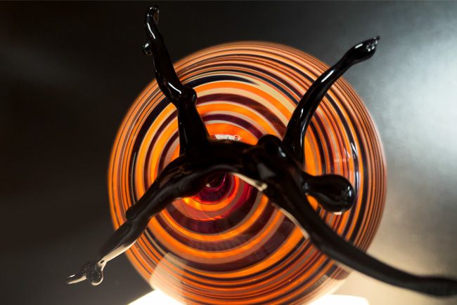 Sculpture en verre, représentant une personne se faisant aspirer dans le mouvement d'une une spirale de lumière